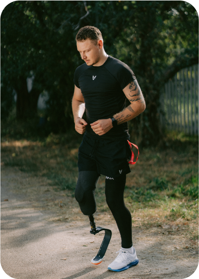 A runner with a prosthetic right leg stands on a road and warms up before the run.