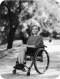 A female participant in a wheelchair smiles and poses for a photo before starting to cover the course.